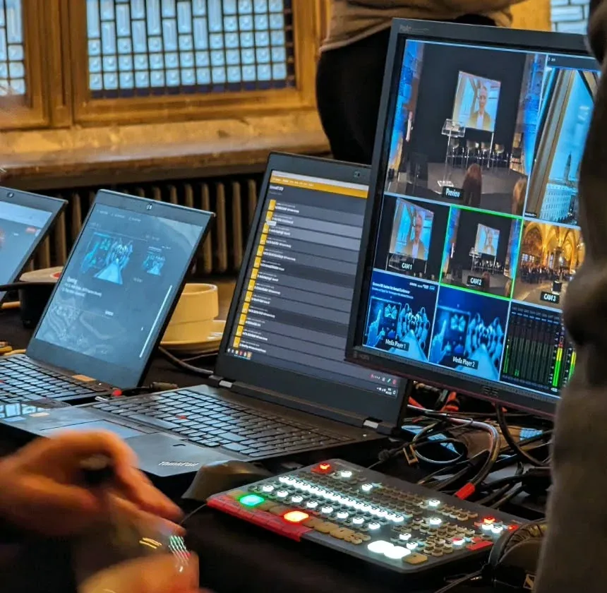Regieplatz mit Bildmischer, Laptops und einem Monitor mit mehreren Kamerabildern